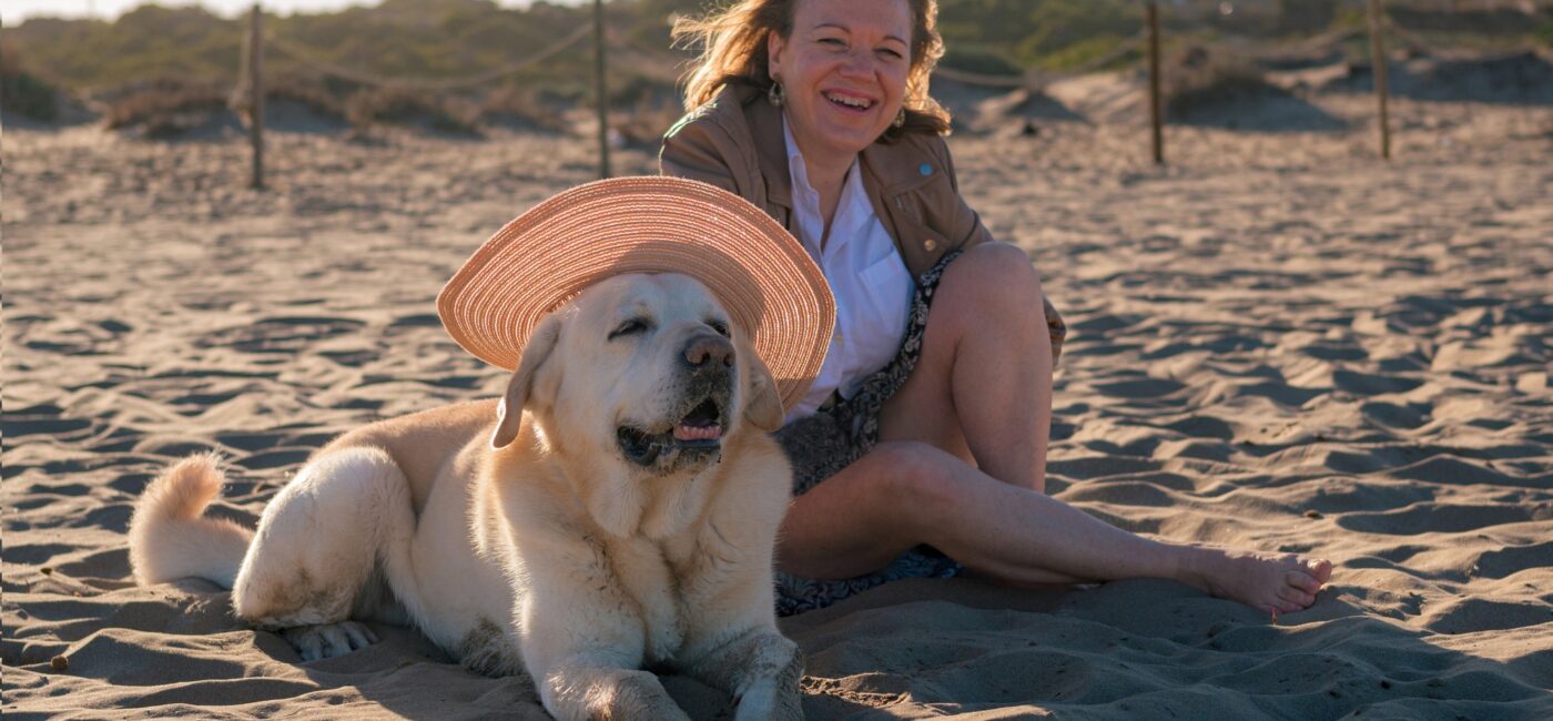 Woman enjoys putting a hat on her dog at the beach